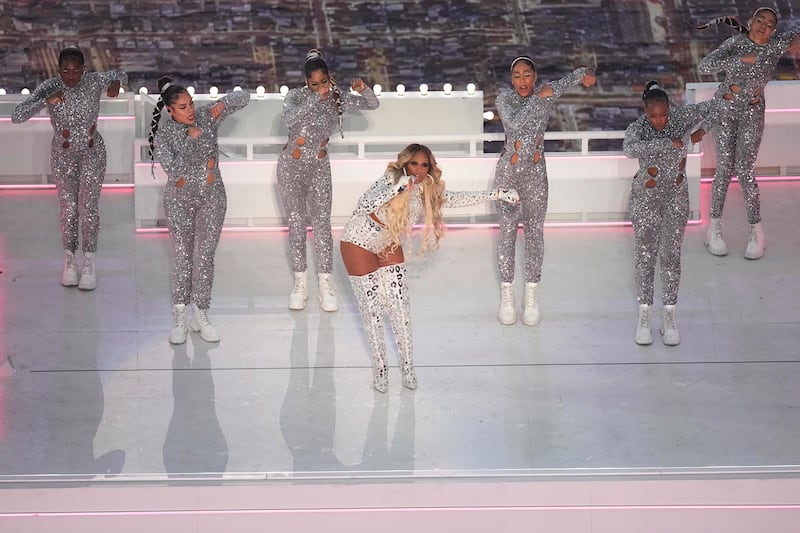 Blige performing 'Family Affair', dressed in a sequinned white outfit with thigh-high boots, accompanied by a sparkling group of backup dancers. AP