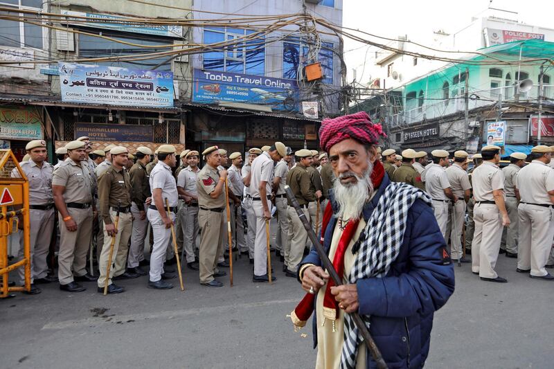 A Muslim man looks on as police officers conduct a flag march in a street outside Jama Masjid. Reuters