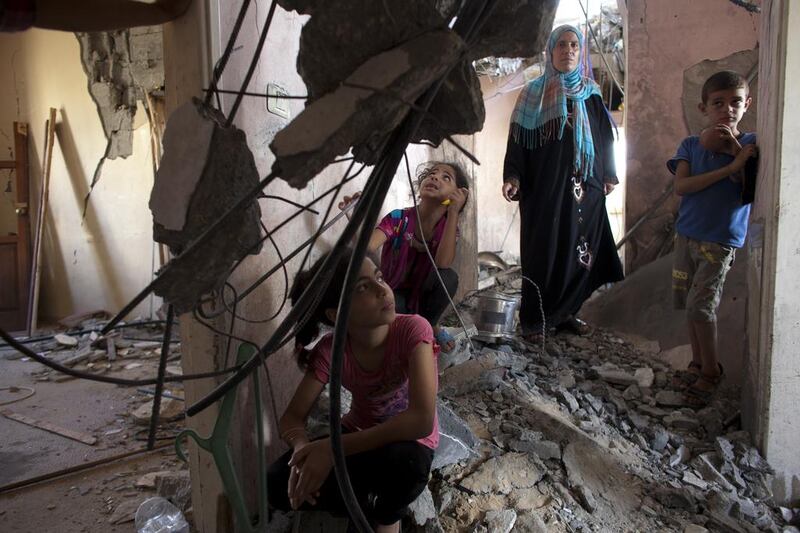 Farida Aziz with her children as they visit their damaged apartment building in the UAE-funded $66m Sheikh Zayed City residential compound in Gaza on August 9,2014. The family was at home on the night of July 14 when the apartment building received an Israeli air strike warning, called a "knock on the roof '. They fled and when they returned the following morning they saw that their home had been destroyed by an Israeli air strike. Heidi Levine for The National