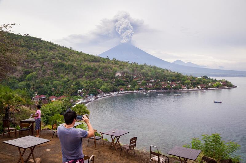 A tourist takes a photo of Mount Agung spewing volcanic ash from the popular Sunset Point in Amed on November 28, 2017 in Karangasem, Island of Bali, Indonesia. Andri Tambunan / Getty Images