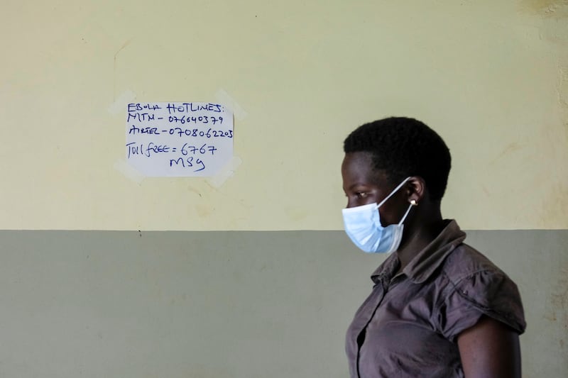 A woman passes a sign with telephone numbers for Ebola help hotlines at the St Florence Clinic in Madudu, near Mubende. AP