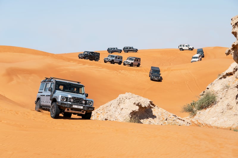 The lead car negotiates a route around desert rocks