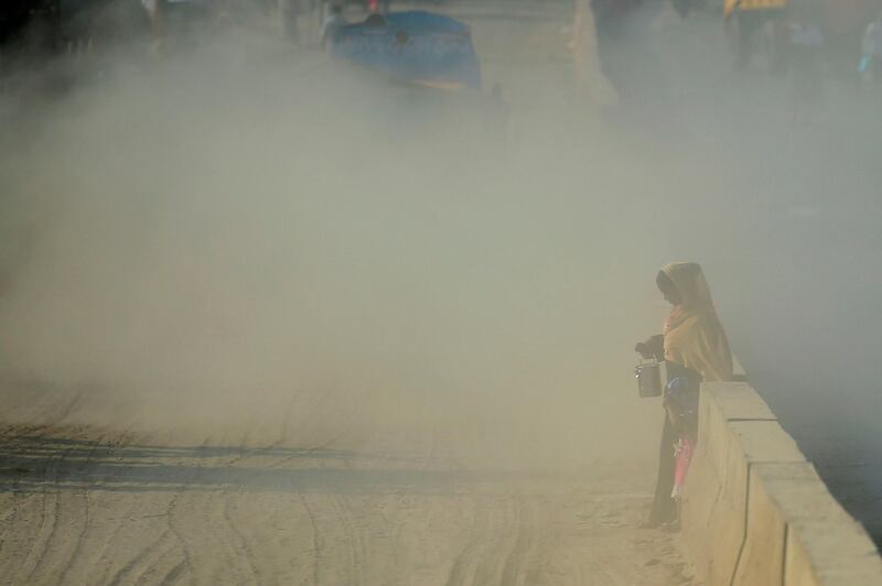 A Bangladeshi woman makes her way along a road under dusty conditions in Dhaka on January 1, 2020. / AFP / MUNIR UZ ZAMAN
