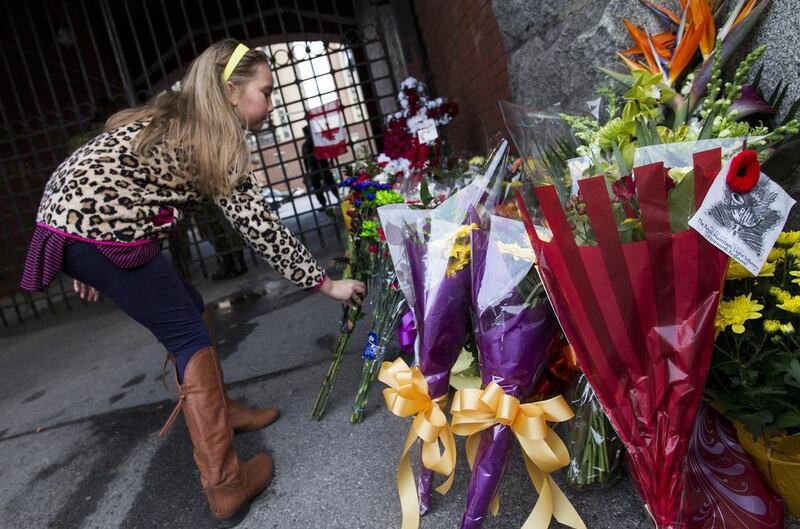 Chloe Hogan, of Hamilton, places flowers at a memorial outside the gates of the John Weir Foote Armory on  October 22, 2014, in memory of Canadian soldier Nathan Cirillo who was killed by a gunman while he was at his post standing guard at the National War Memorial near Parliament Hill in Ottawa. Aaron Lynett/The Canadian Press