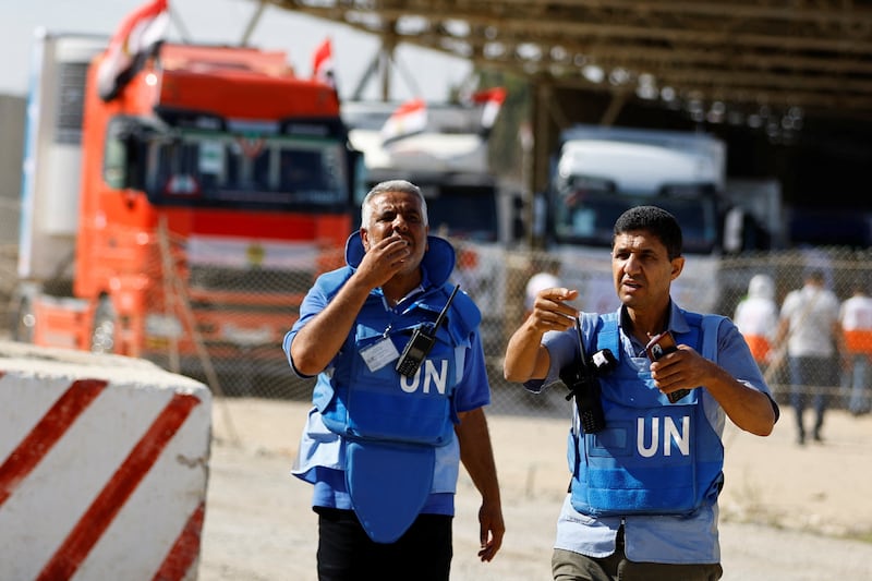 UN workers gesture as lorries carrying aid arrive at the Palestinian side of the border with Egypt on October 21.  Reuters