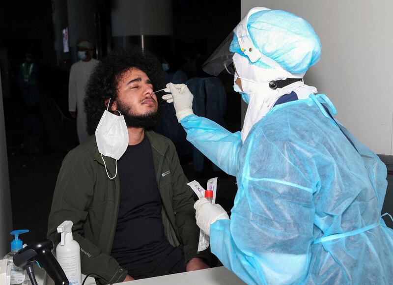 A medical worker collects a swab sample from a passenger for a RT-PCR Coronavirus test at the Muscat international airport in the Omani capital on October 1, 2020. (Photo by MOHAMMED MAHJOUB / AFP)