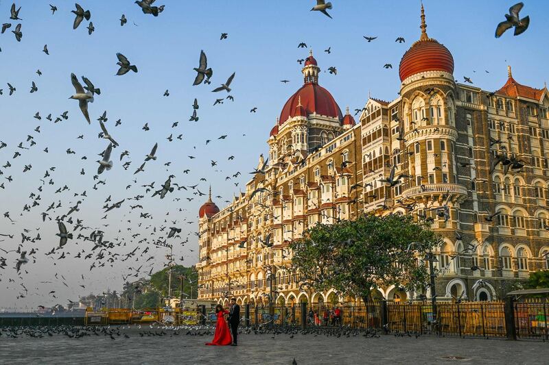 TOPSHOT - A couple poses for photographs in front of the Taj Mahal hotel in Mumbai on March 4, 2021. / AFP / Punit PARANJPE
