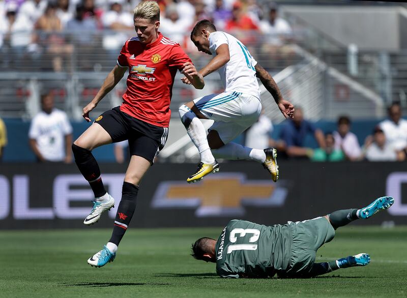 Manchester United's Scott McTominay, left, and Real Madrid's Fabio Coentrao jump over Real Madrid goalie Francisco Casilla. Ben Margot / AP Photo