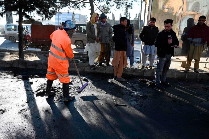 Onlookers watch a municipal worker remove debris from a street after multiple rockets were fired in the Afghan capital Kabul on December 12, 2020. AFP