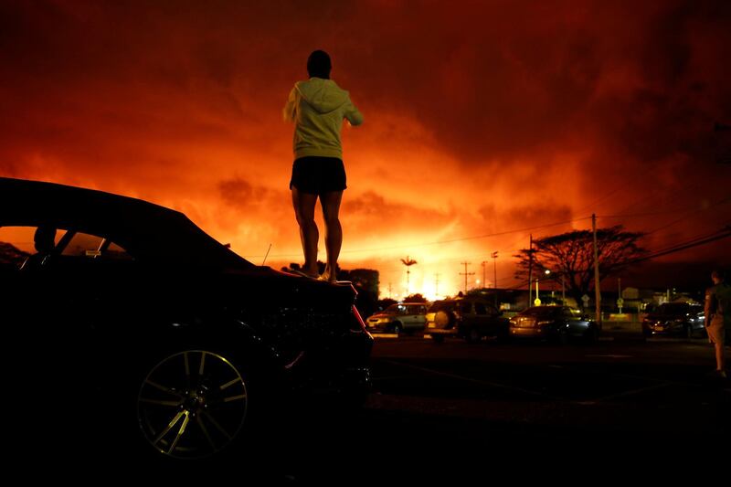 Lara Jackson, 34, of Manchester, Britain, takes a photo as lava lights up the sky above Pahoa during ongoing eruptions of the Kilauea Volcano in Hawaii. Terray Sylvester / Reuters