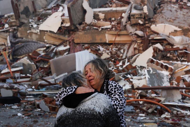 Two people cry near rubble in Turkey's Hatay province. Reuters