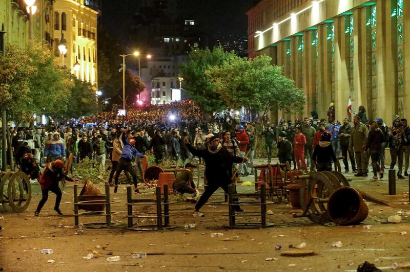 Protesters throw stones at riot police during clashes in central Beirut.  EPA