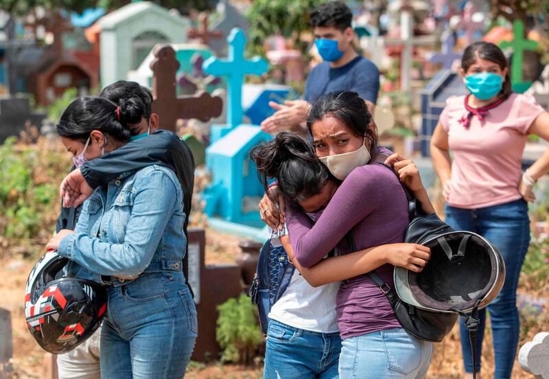 Relatives and friends of a mechanic called Roberto, who died at a hospital with symptoms of the novel coronavirus, COVID-19 and did not have a wake before his burial, cry at the Milagro de Dios Cemetery in Managua.  AFP