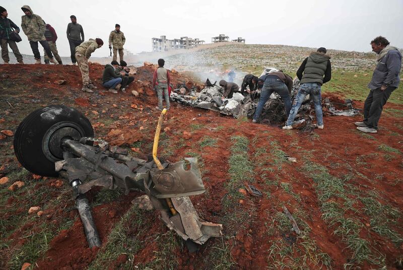 People search for scrapes of metal among the debris of a Syrian military helicopter that was shot down on February 14, 2020, in the western countryside of Aleppo province. AFP