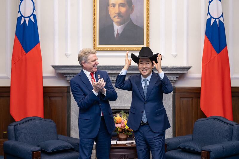 Taiwan's President Lai Ching-te puts on a hat received from US representative Michael McCaul during a meeting at the Presidential Office in Taipei. AFP
