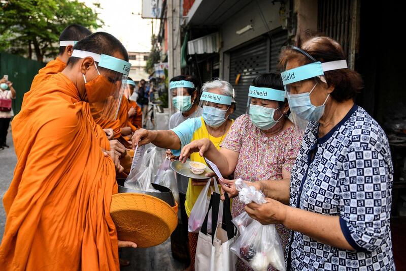 Buddhist monks wearing face shields and mask to protect themselves from the coronavirus disease (COVID-19) collect alms in Bangkok, Thailand. REUTERS