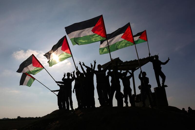 TOPSHOT - Palestinian protesters wave their national flag near the Israel-Gaza border east of the southern Gaza Strip city of Khan Yunis as they demonstrate against calls for the closure of UNRWA by the Israeli prime minister and cuts in Palestinian aid by the American president on January 9, 2018. / AFP PHOTO / SAID KHATIB