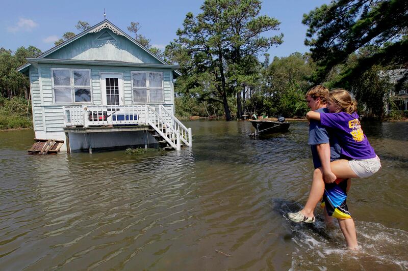 Residents of Stumpy Point, N.C. make their way into their flooded home following the effects of Hurricane Irene Sunday, Aug. 28, 2011.  Flood waters rose all across New Jersey on Sunday, closing roads from side streets to major highways as Hurricane Irene weakened and moved on, leaving 600,000 homes and businesses without power. (AP Photo/Gerry Broome) *** Local Caption ***  APTOPIX Irene.JPEG-021f1.jpg