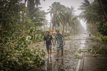 Residents brave rains and strong wind as they walk past uprooted trees along a highway in Can-avid town, Eastern Samar province, central Philippines on May 14, 2020, as Typhoon Vongfong makes landfall. A powerful typhoon hit the central Philippines on May 14, forcing a complicated and risky evacuation for tens of thousands already hunkered down at home during the coronavirus pandemic. Because of the twin threat of the storm and the virus, evacuation centres in the central Philippines will only accept half their capacity and evacuees will have to wear facemasks. / AFP / Alren BERONIO