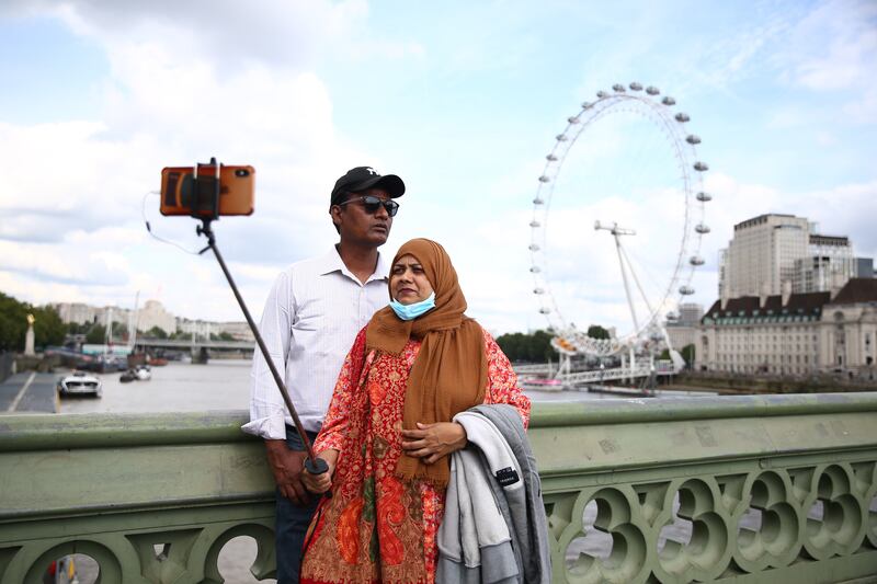 People take photos at Westminster Bridge in London. The British health minister has said that the country will not be imposing a Covid-19 'vaccine passport' system to verify vaccination status at concerts, nightclubs and other venues. Getty Images
