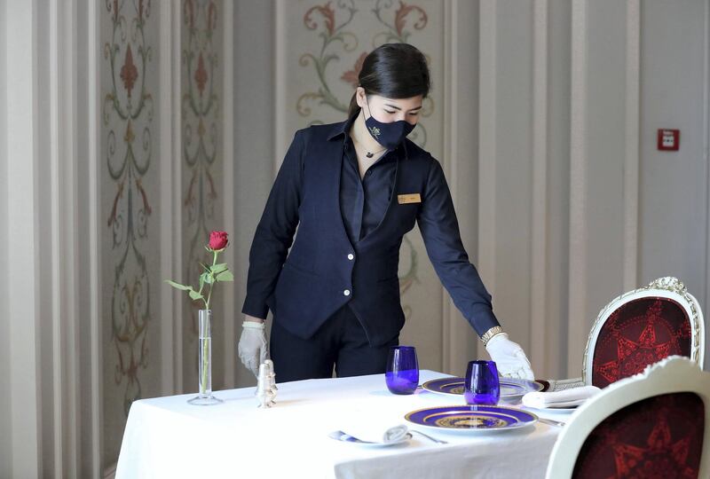 Dubai, United Arab Emirates - Reporter: N/A. Coronavirus/Covid-19. Waitress at Vanitas, Nina Manalo wears a branded mask as she straightens a table at the Palazzo Versace hotel. Sunday, June 7th, 2020. Dubai. Chris Whiteoak / The National