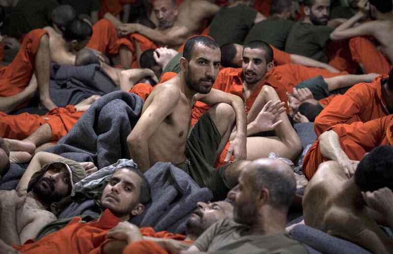 (FILES) In this file photo taken on October 26, 2019,  men, accused of being affiliated with the Islamic State (IS) group, sit on the floor in a prison in the northeastern Syrian city of Hasakeh. As it enters its tenth year, the war in Syria is anything but abating as foreign powers scrap over a ravaged country where human suffering keeps reaching new levels. / AFP / FADEL SENNA
