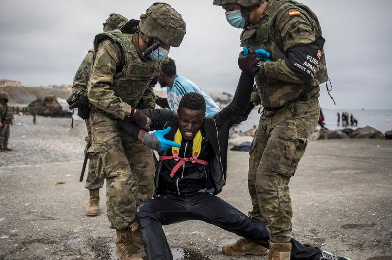 A man is held by soldiers of the Spanish Army at the border of Morocco and Spain at the Spanish enclave of Ceuta. A record 6,000 migrants entered Ceuta illegally on Monday, 1,500 of whom were minors. AP Photo