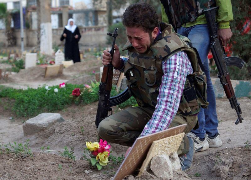 FILE PHOTO: A Free Syrian Army fighter mourns at the grave of his father who was killed by what activists said was shelling by forces loyal to Syria's President Bashar al-Assad, in a public park that has been converted into a makeshift graveyard in Deir el-Zor, Syria March 11, 2013. REUTERS/Khalil Ashawi/File Photo