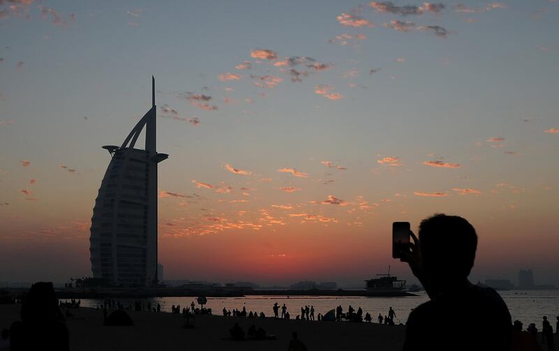 A man takes pictures after the last sunset of 2018 near Burj Al Arab hotel in Dubai, United Arab Emirates December 31, 2018. REUTERS/Suhaib Salem