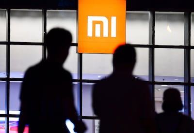 (FILES) This file picture taken on June 12, 2018 shows people walking pass a Xiaomi smartphone and technology store in Shenyang in China's northeastern Liaoning province. Chinese smartphone maker Xiaomi kicked off its initial public offering on June 21 but the firm is likely to pull in about 6.1 billion USD, far less than originally expected, with investors having mixed views about its main business. - China OUT
 / AFP / -
