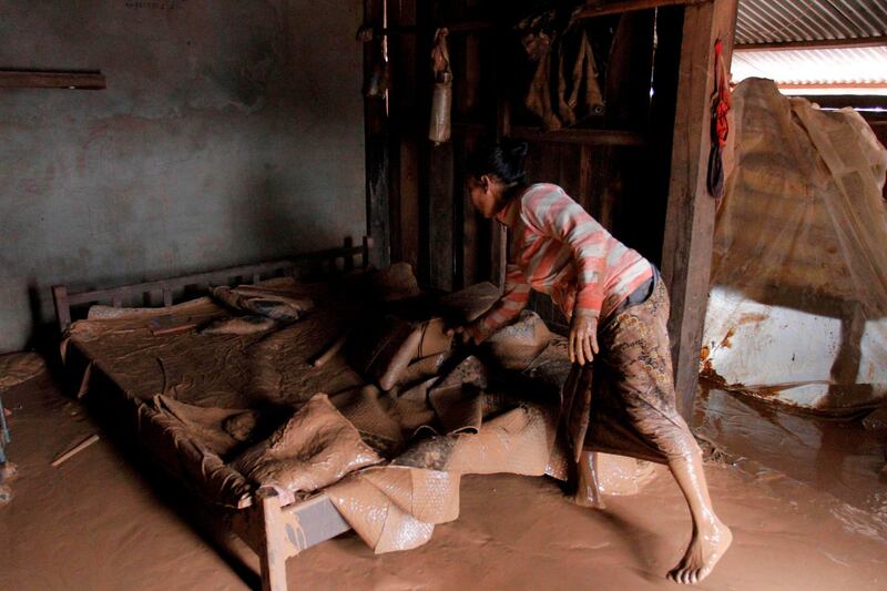 A woman salvages her belongings from her flooded home at a village in Sanamxai, Attapeu province. AFP