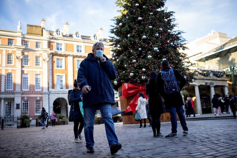 Pedestrians wearing a protective face covering walk past a Christmas tree in Covent Garden in central London. AFP