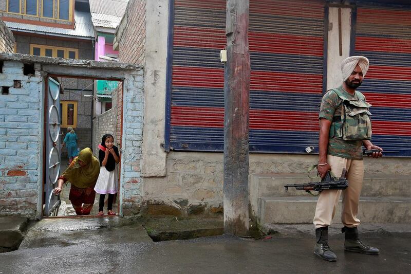A girl peers from her house as a member of the security forces patrols a street in Srinagar, Kashmir. Cathal McNaughton / Reuters