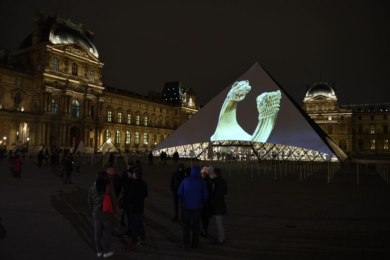 Images of the art displayed in the Louvre Abu Dhabi are projected onto the Louvre Pyramid in Paris Wednesday night to mark the opening of the museum on Saadiyat island. Eric Feferberg / AFP