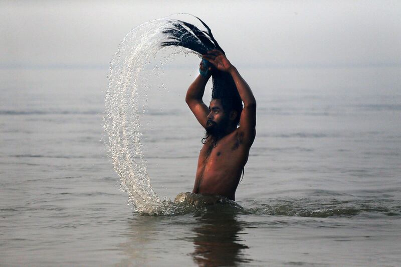 An Indian Hindu holy man, or Naga Sadhu, swings his head as he bathes at Sangam, the confluence of the rivers Ganges, Yamuna and mythical Saraswati, during the royal bath on Makar Sankranti at the start of the Maha Kumbh Mela in Allahabad, India, Monday, Jan. 14, 2013. Millions of Hindu pilgrims are expected to take part in the large religious congregation that lasts more than 50 days on the banks of Sangam during the Maha Kumbh Mela in January 2013, which falls every 12th year. (AP Photo/Kevin Frayer) *** Local Caption ***  India Maha Kumbh Mela.JPEG-0228f.jpg