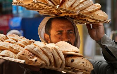 A bread seller carries a tray of Egypt's traditional 'baladi' flatbread outside a bakery, in Cairo. AP
