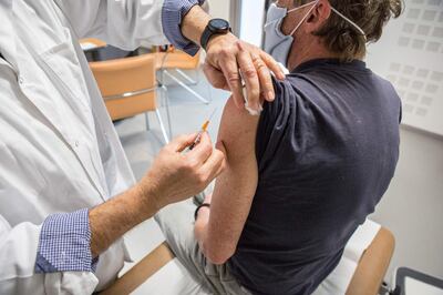 General practitioner Jean Louis Bensoussan, administers a dose of AstraZeneca Covid-19 vaccine to a patient, in Gragnague near Toulouse, southern France, on February 26, 2021. Private practitioners in France started vaccinating vulnerable patients between 50 and 64 at their medical offices on February 25, as part of a new stage in the country's Covid-19 vaccination campaign. / AFP / Fred SCHEIBER
