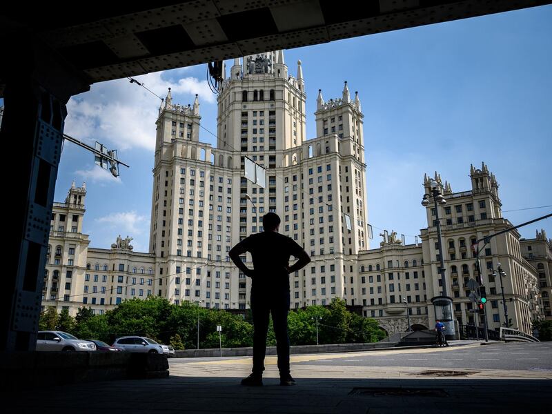 A man stands at a street with a Stalin-era skyscraper in the background in Moscow, Russia. AFP