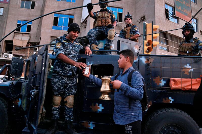 A street vendor sells coffee to the Iraqi Federal police as they deployed in Sadr City, Baghdad, Iraq. Iraq's prime minister on Monday ordered the police to replace the army in Sadr City, a heavily populated Shiite neighborhood of Baghdad where dozens of people were killed or wounded in weekend clashes stemming from anti-government protests. AP Photo