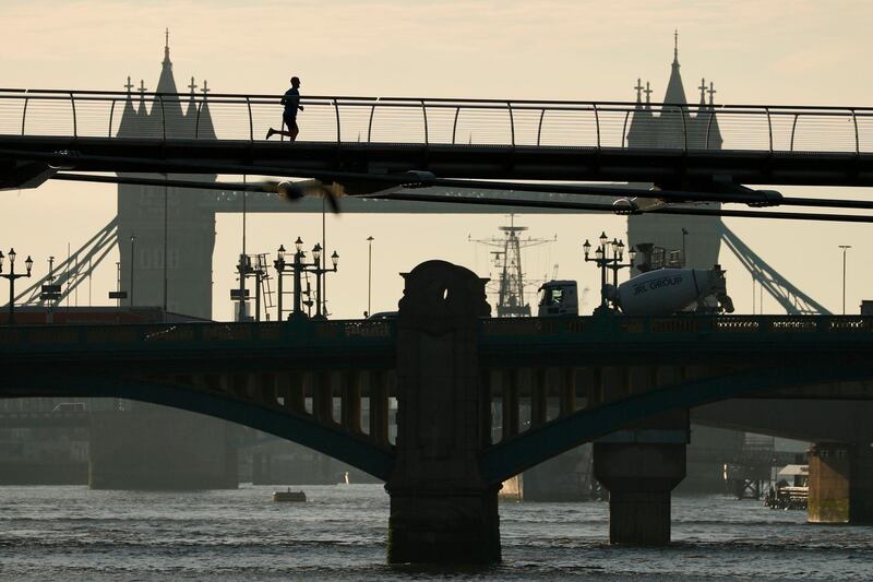 A jogger runs across the Millennium Footbridge over the River Thames in central London. AFP