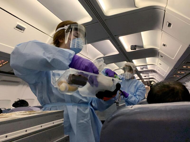 Flight attendants wearing protective clothing and masks serve snacks to Canadians, who had been evacuated from China due to the outbreak of novel Coronavirus on an American charter plane, on another aircraft taking them to Canadian Forces Base (CFB) Trenton, from Vancouver International Airport in Richmond, British Columbia, Canada. Reuters