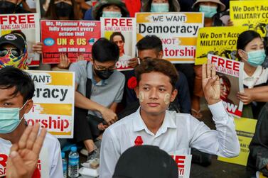 Anti-coup protesters flash the three-fingered salute of resistance and display pictures of deposed Myanmar leader Aung San Suu Kyi in Yangon, Myanmar on February 25, 2021. AP