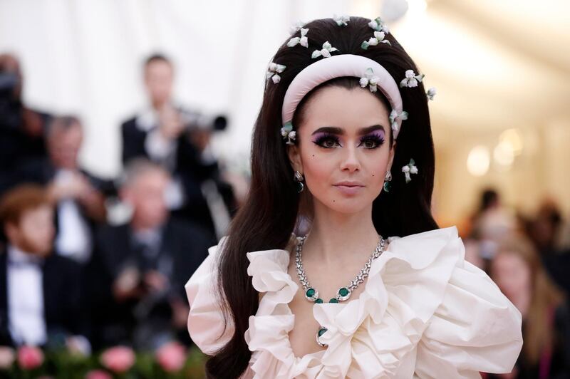 Actress Lily Collins took beauty cues from the 1960s with dramatic, Twiggy-esque lashes, pale lips and a theatrical bouffant, scattered with petals. Reuters