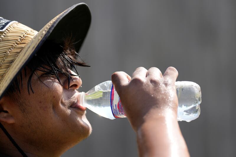 Carlos Rodriguez drinks water during a break from digging fence post holes on June 27 in Houston, Texas.  AP