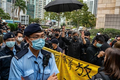 HONG KONG, HONG KONG - MARCH 1: Pro-democracy supporters line up outside the West Kowloon court as police officers patrol on March 1, 2021 in Hong Kong. The protest took place during the court appearances by dozens of dissidents charged with subversion in the largest use of Beijing's sweeping new the national security law to date. (Photo by Anthony Kwan/Getty Images)