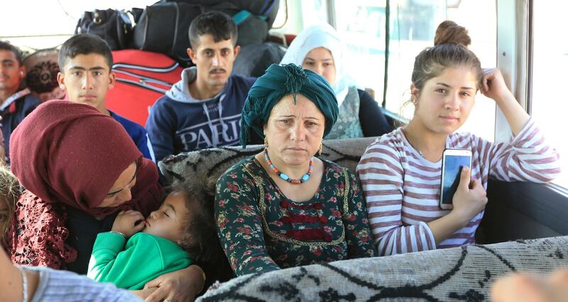 Syrian displaced families, who fled violence after the Turkish offensive against Syria, sit in a bus on their way to camps on the outskirts of Dohuk, Iraq. REUTERS