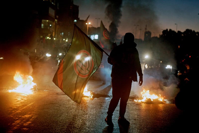epaselect epa06484383 A supporter of Lebanese Parliament Speaker Nabih Berri and Amal movement carries the party's flag near burning tires during a protest in Beirut, Lebanon, 29 January 2018. Protests erupted following a row over a leaked video in which Foreign Minister Gebran Bassil allegedly calls Parliament Speaker Nabih Berri a 'thug' in a closed meeting at the southern suburb.  EPA/WAEL HAMZEH