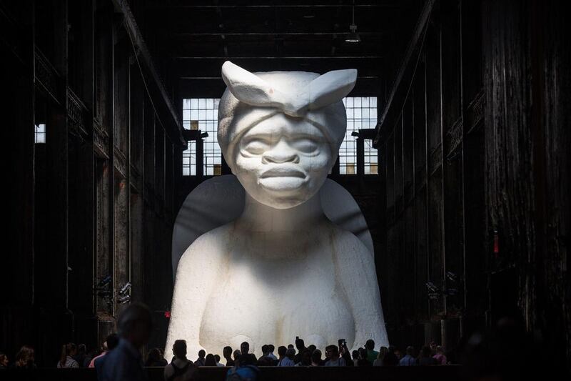 People view Kara Walker’s “A Subtlety,” a seventy-five and a half feet long and thirty-five and a half feet tall sphinx made in part of bleached sugar at the former Domino Sugar Refinery. Andrew Burton / Getty Images