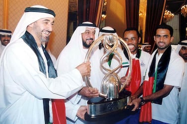 The Crown Prince of Abu Dhabi Khalifa Bin Zayed (2nd, L) and UAE Chief of Staff Mohammed Bin Zayed (L) smile as they pose with Emirati players of Al-Ain club as they hold up the winner's Cup of the Asian Champions League, upon their arrival from Bangkok to Abu Dhabi airport 12 October 2003. AFP PHOTO/WAM/HO (Photo by WAM / AFP)