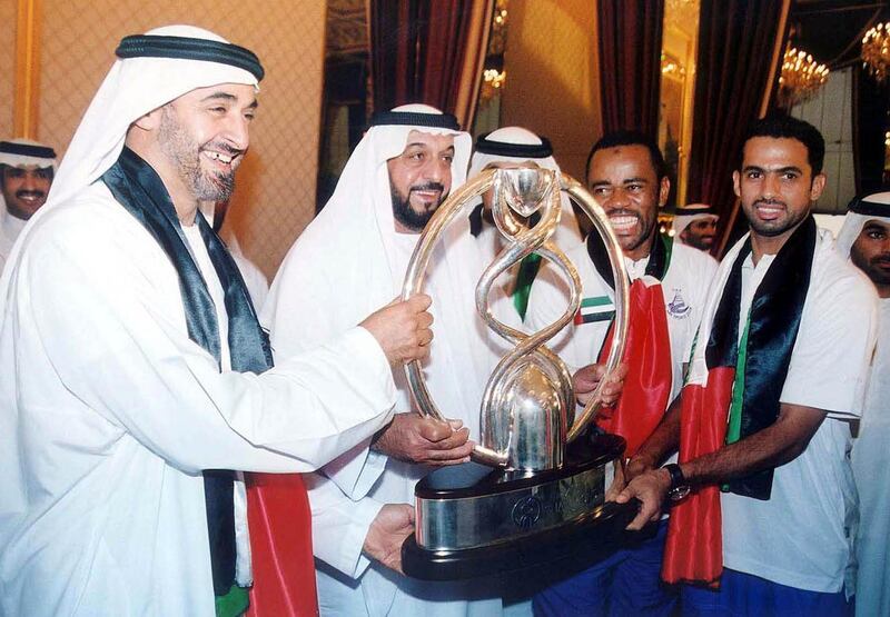 The Crown Prince of Abu Dhabi Khalifa Bin Zayed (2nd, L) and UAE Chief of Staff  Mohammed Bin Zayed (L) smile as they pose with Emirati players of Al-Ain club as they hold up the winner's Cup of the Asian Champions League, upon their arrival from Bangkok to Abu Dhabi airport 12 October 2003. AFP PHOTO/WAM/HO (Photo by WAM / AFP)